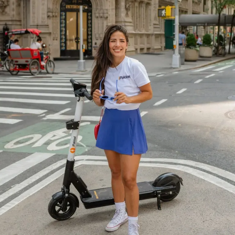 Rider standing with an iPakket e-scooter at a Manhattan crosswalk