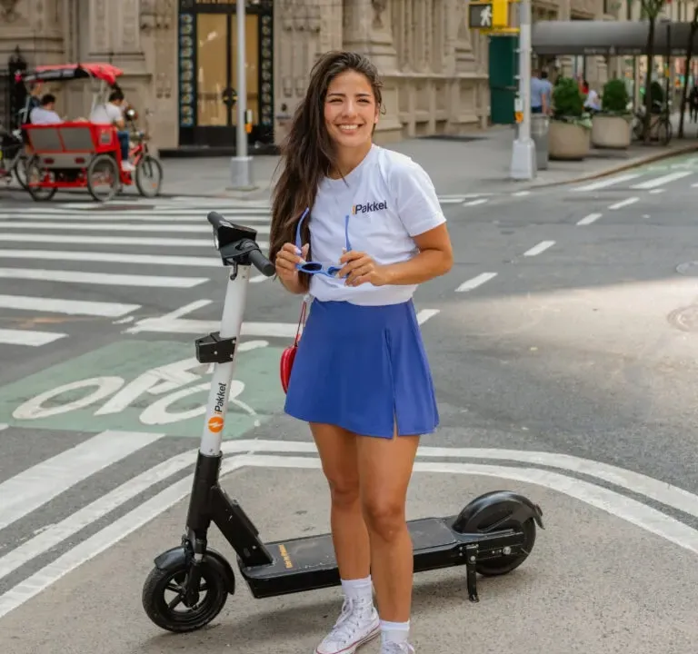 Rider standing with an iPakket e-scooter at a Manhattan crosswalk