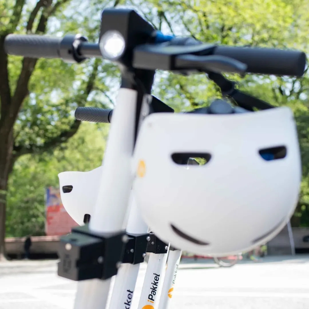 Close-up of Ride by iPakket helmets locked to the handlebars of two shared e-scooters