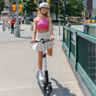 Rider on a Ride by iPakket e-scooter beside a New York City subway entrance